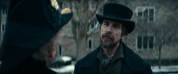 Movie still from “The Pale Blue Eye” (2022), directed by Scott Cooper – A man in a top hat and a long beard; Close Up shot, Over the shoulder angle