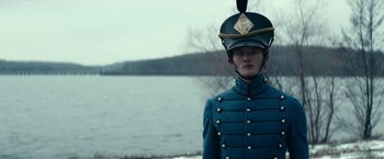 Movie still from “The Pale Blue Eye” (2022), directed by Scott Cooper – A man in a uniform stands in front of a body of water; Medium shot, Over the shoulder angle