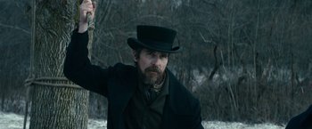 Movie still from “The Pale Blue Eye” (2022), directed by Scott Cooper – A man in a top hat and a long beard; Close Up shot, Over the shoulder angle