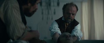 Movie still from “The Pale Blue Eye” (2022), directed by Scott Cooper – A man in a vest and tie looking at another man in a suit; Medium shot, Over the shoulder angle