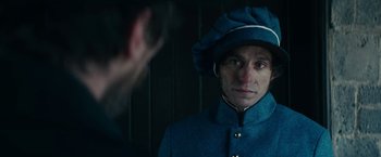 Movie still from “The Pale Blue Eye” (2022), directed by Scott Cooper – A man wearing a blue coat and a blue hat; Close Up shot, Over the shoulder angle