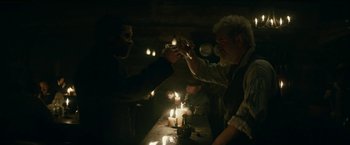 Movie still from “The Pale Blue Eye” (2022), directed by Scott Cooper – A group of people sitting at a table with lit candles; Medium shot, Over the shoulder angle