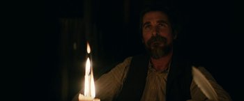 Movie still from “The Pale Blue Eye” (2022), directed by Scott Cooper – A man holding a lit candle in a dark room; Close Up shot, Over the shoulder angle