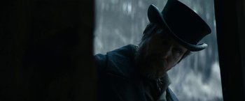 Movie still from “The Pale Blue Eye” (2022), directed by Scott Cooper – A man with a beard wearing a hat and a jacket; Close Up shot, Over the shoulder angle