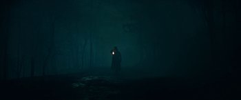 Movie still from “The Pale Blue Eye” (2022), directed by Scott Cooper – A person standing in the dark holding a flashlight; Extreme Wide shot, Low angle