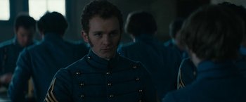 Movie still from “The Pale Blue Eye” (2022), directed by Scott Cooper – A man in a military uniform standing in front of a group of people; Close Up shot, Over the shoulder angle