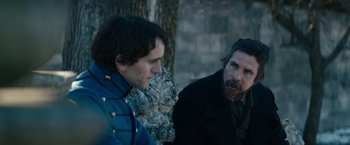 Movie still from “The Pale Blue Eye” (2022), directed by Scott Cooper – Two men sitting next to each other on a bench; Medium shot, Over the shoulder angle