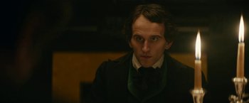 Movie still from “The Pale Blue Eye” (2022), directed by Scott Cooper – A man in a suit and bow tie looking at the camera; Close Up shot, Over the shoulder angle