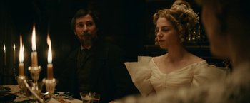 Movie still from “The Pale Blue Eye” (2022), directed by Scott Cooper – A man and a woman sitting at a dinner table; Medium shot, Over the shoulder angle