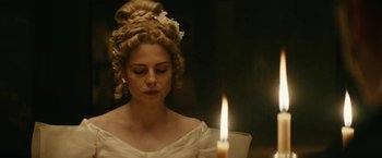 Movie still from “The Pale Blue Eye” (2022), directed by Scott Cooper – A woman in a white dress is looking at a candle; Close Up shot, Low angle