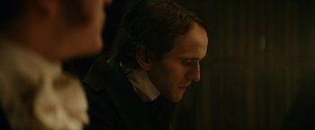 Movie still from “The Pale Blue Eye” (2022), directed by Scott Cooper – A person wearing a suit and tie; Close Up shot, Over the shoulder angle