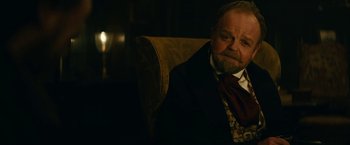 Movie still from “The Pale Blue Eye” (2022), directed by Scott Cooper – An older man sitting in a chair in a dark room; Close Up shot, Over the shoulder angle
