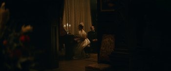 Movie still from “The Pale Blue Eye” (2022), directed by Scott Cooper – A man and a woman sitting in front of a grand piano; Wide shot, Over the shoulder angle