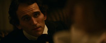 Movie still from “The Pale Blue Eye” (2022), directed by Scott Cooper – A person wearing a suit and tie; Close Up shot, Over the shoulder angle