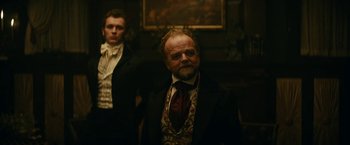 Movie still from “The Pale Blue Eye” (2022), directed by Scott Cooper – A man with a goatee and a beard wearing a suit and tie; Medium shot, Low angle