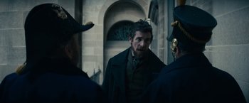 Movie still from “The Pale Blue Eye” (2022), directed by Scott Cooper – A group of men standing next to each other in front of a building; Medium shot, Over the shoulder angle