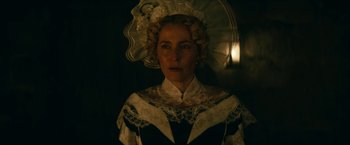 Movie still from “The Pale Blue Eye” (2022), directed by Scott Cooper – A woman in a victorian dress with a parasol in a dark room; Close Up shot, Over the shoulder angle