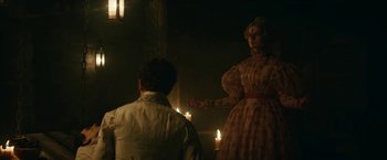 Movie still from “The Pale Blue Eye” (2022), directed by Scott Cooper – A man and a woman standing next to lit candles in a dark room; Medium shot, Over the shoulder angle