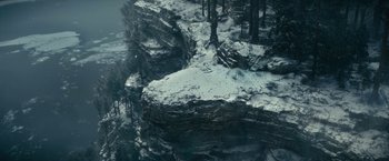 Movie still from “The Pale Blue Eye” (2022), directed by Scott Cooper – A view from above of a rocky cliff with snow on the ground; Extreme Wide shot, Overhead angle