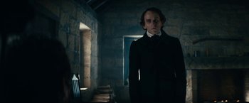 Movie still from “The Pale Blue Eye” (2022), directed by Scott Cooper – A man in a black jacket standing in a room; Medium shot, Low angle