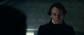 Movie still from “The Pale Blue Eye” (2022), directed by Scott Cooper – A man in a black coat and a white shirt; Close Up shot, Over the shoulder angle