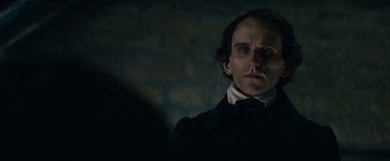 Movie still from “The Pale Blue Eye” (2022), directed by Scott Cooper – A man in a black shirt and a white shirt looking to his left; Close Up shot, Over the shoulder angle