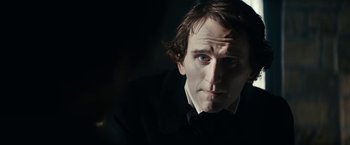 Movie still from “The Pale Blue Eye” (2022), directed by Scott Cooper – A person wearing a suit and tie; Close Up shot, Over the shoulder angle