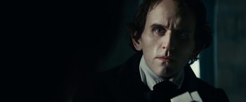 Movie still from “The Pale Blue Eye” (2022), directed by Scott Cooper – A person wearing a suit and tie; Close Up shot, Over the shoulder angle