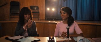 Movie still from “The Prom” (2020), directed by Ryan Murphy – Two women sitting at a table in front of microphones; Medium shot, Over the shoulder angle