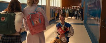Movie still from “The Prom” (2020), directed by Ryan Murphy – A man sitting on the ground in front of a crowd; Medium shot, High angle