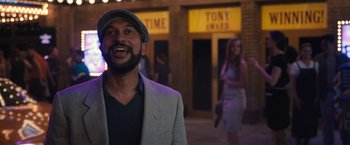 Movie still from “The Prom” (2020), directed by Ryan Murphy – A man with a beard wearing a suit and a hat; Medium shot, Over the shoulder angle