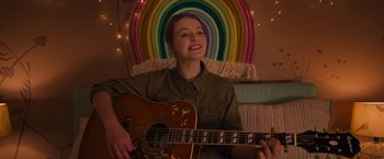 Movie still from “The Prom” (2020), directed by Ryan Murphy – A woman sitting in front of a rainbow holding a guitar; Medium shot, Over the shoulder angle