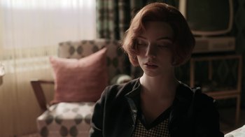Movie still from “The Queen's Gambit” (2020), directed by Scott Frank – A woman with red hair is sitting in front of a chair; Close Up shot, Over the shoulder angle