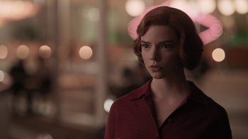 Movie still from “The Queen's Gambit” (2020), directed by Scott Frank – A woman in a red shirt standing in front of a window; Close Up shot, Over the shoulder angle