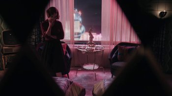 Movie still from “The Queen's Gambit” (2020), directed by Scott Frank – A woman is sitting in front of a window in a living room; Wide shot, High angle