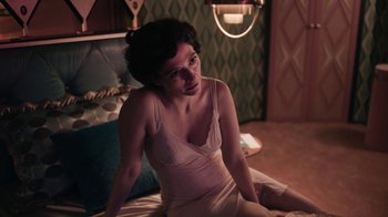 A woman sitting on a bed wearing a white dress
