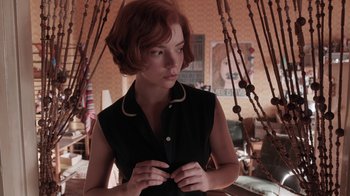 Movie still from “The Queen's Gambit” (2020), directed by Scott Frank – A woman with red hair holding a knife in her hands; Medium shot, Over the shoulder angle