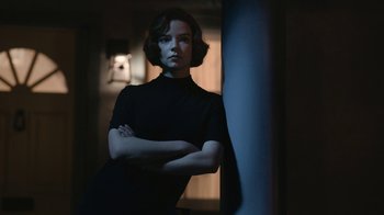 Movie still from “The Queen's Gambit” (2020), directed by Scott Frank – A woman standing next to a wall with her arms crossed; Medium shot, Low angle