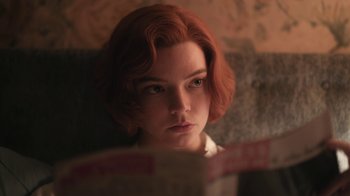 Movie still from “The Queen's Gambit” (2020), directed by Scott Frank – A woman with red hair is reading a book; Close Up shot, Low angle