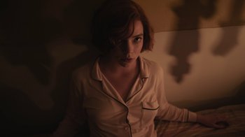Movie still from “The Queen's Gambit” (2020), directed by Scott Frank – A woman in a white shirt is sitting on a bed; Close Up shot, High angle