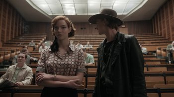 Movie still from “The Queen's Gambit” (2020), directed by Scott Frank – A man and a woman standing next to each other in a lecture hall; Medium shot, Over the shoulder angle