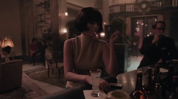 Movie still from “The Queen's Gambit” (2020), directed by Scott Frank – A woman sitting at a table with a glass of milk; Medium shot, Over the shoulder angle