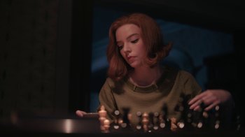 Movie still from “The Queen's Gambit” (2020), directed by Scott Frank – A woman sitting in front of a chess board; Medium shot, High angle