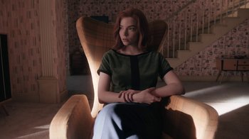 Movie still from “The Queen's Gambit” (2020), directed by Scott Frank – A woman sitting in a chair with her hands crossed; Medium shot, High angle
