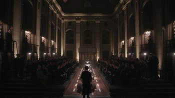 Movie still from “The Queen's Gambit” (2020), directed by Scott Frank – A man standing in front of a group of people in an auditorium; Extreme Wide shot, High angle