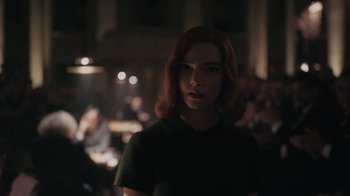 Movie still from “The Queen's Gambit” (2020), directed by Scott Frank – A woman with red hair is standing in a dark room; Close Up shot, Over the shoulder angle