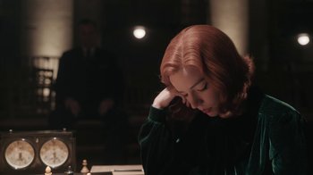 Movie still from “The Queen's Gambit” (2020), directed by Scott Frank – A woman sitting in front of a chess board with her head resting on her hand; Close Up shot, Over the shoulder angle