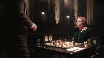 Movie still from “The Queen's Gambit” (2020), directed by Scott Frank – Two people are playing a game of chess in a darkened room; Medium shot, Over the shoulder angle