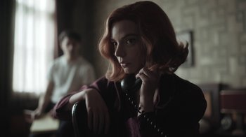 Movie still from “The Queen's Gambit” (2020), directed by Scott Frank – A woman with red hair is holding a phone; Medium shot, Low angle
