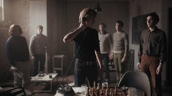Movie still from “The Queen's Gambit” (2020), directed by Scott Frank – A group of men standing around a chess board; Medium shot, Low angle
